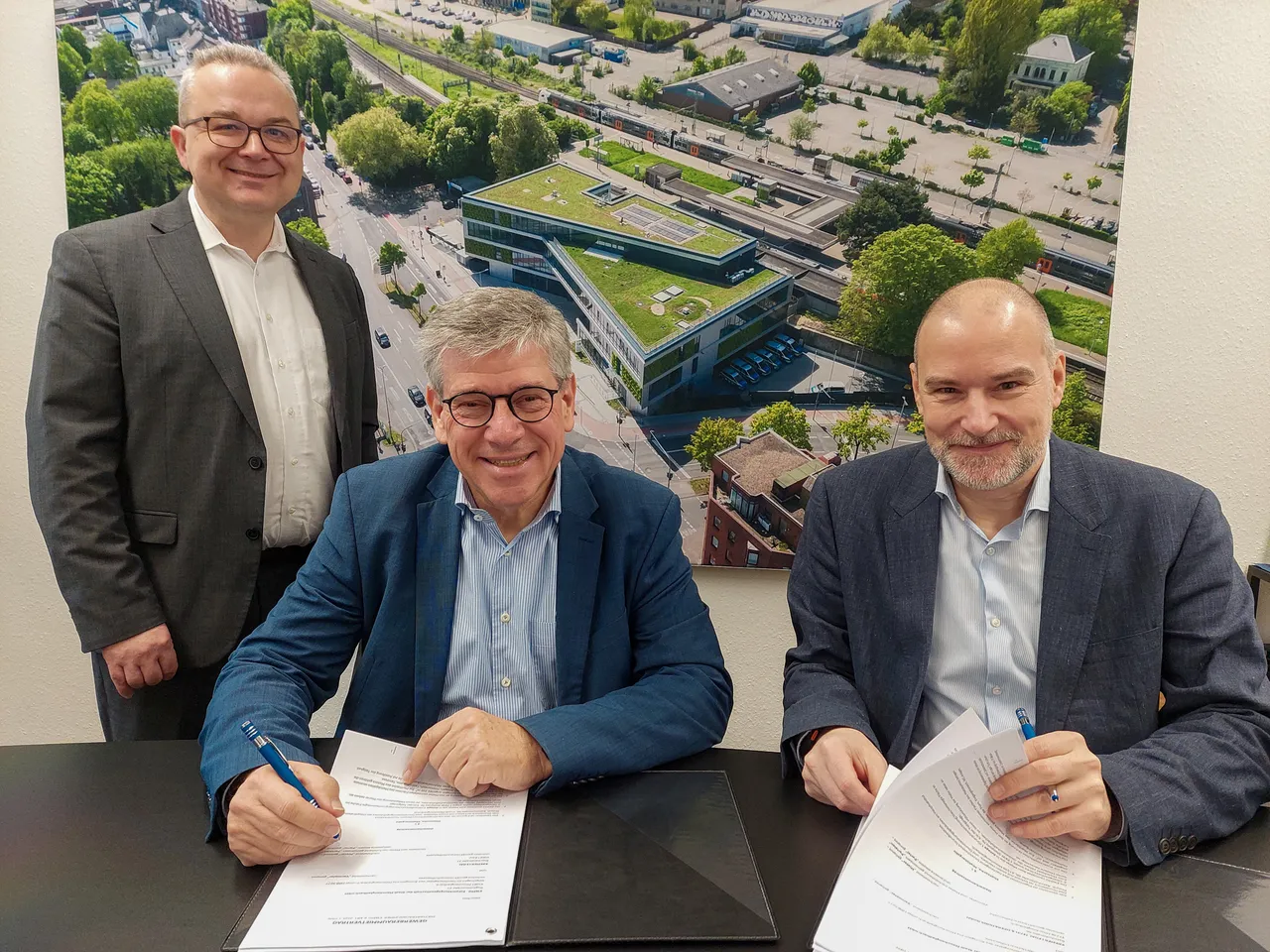 Sascha Kremer (Gründer KREMER LEGAL) bei der Vertragsunterzeichnung mit Ulrich Schückhaus, Vorsitzender der Geschäftsführung von EWMG und WFMG, sowie Rafael Lendzion, Teamleiter Unternehmensservice der WGMG (v. r.).